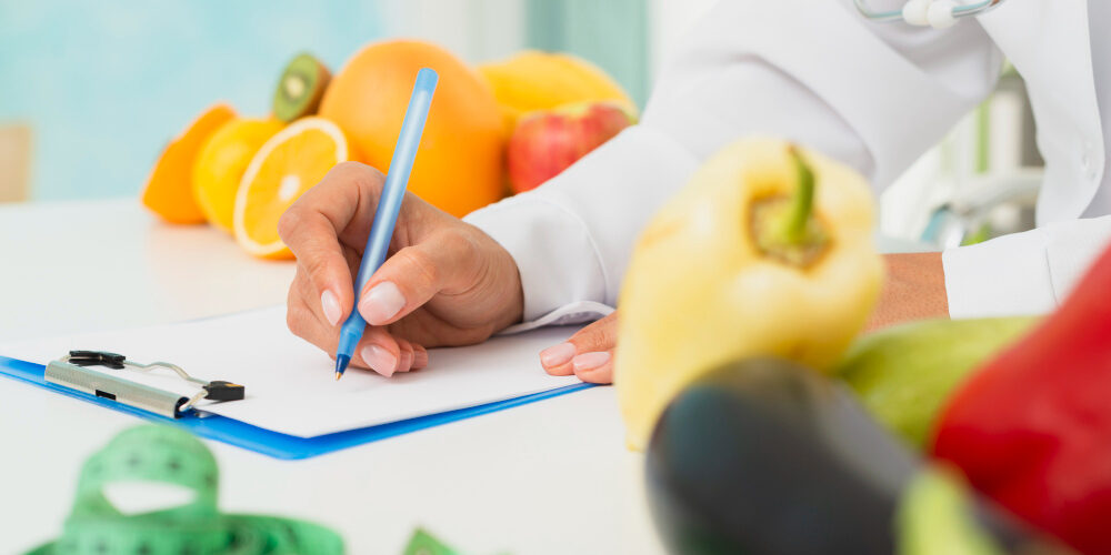 Consultation diététique avec rédaction de plan nutritionnel, fruits frais et mètre ruban.