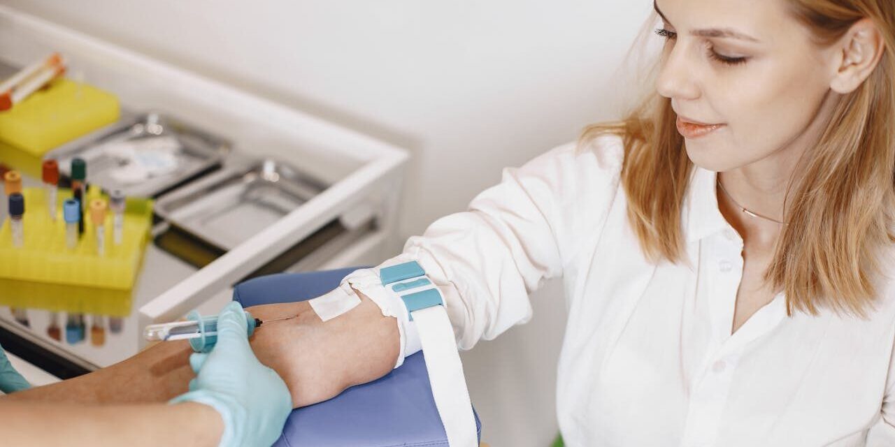 Infirmière effectuant une prise de sang sur une patiente souriante.